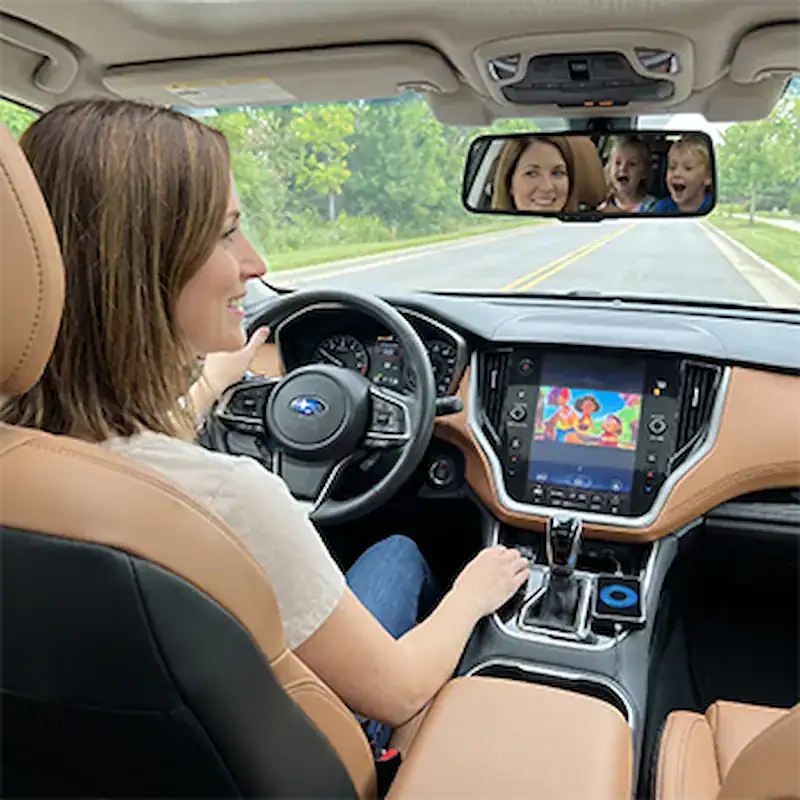 Femme conduisant tranquillement pendant que les enfants regardent l'écran de voiture via Roadcast