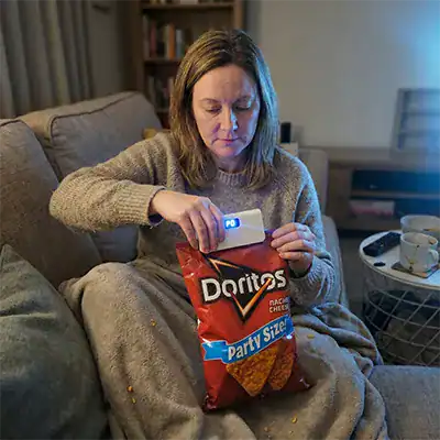 Femme utilisant le SnapSeal Mini Sealer sur un sachet de chips