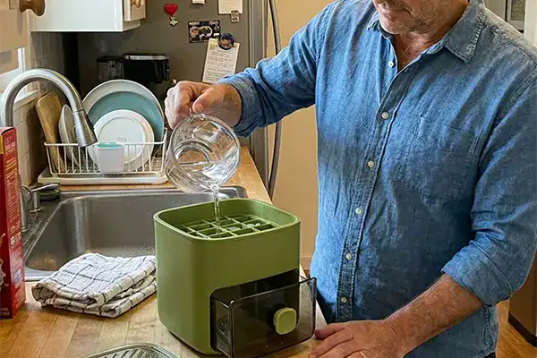Homme utilise le CubeNest pour préparer une boisson dans la cuisine